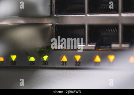 Eine Detailaufnahme eines Netzwerk-Switches mit eingesteckten Kabeln und LED-Anzeigen. Stockfoto