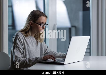 Junge schöne Frau freiberuflich müde arbeiten in der Nacht auf einem Laptop, schließt Arbeit spät Stockfoto