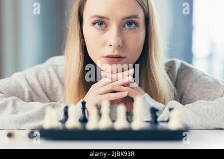 Nahaufnahme eines Bildportraits von einer jungen schönen Frau, die zu Hause Schach spielt, studiert, denkt, konkurrierend, in Quarantäne Stockfoto