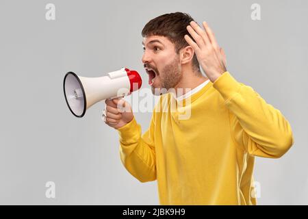 Wütender Mann, der zu einem Megaphon schreit Stockfoto