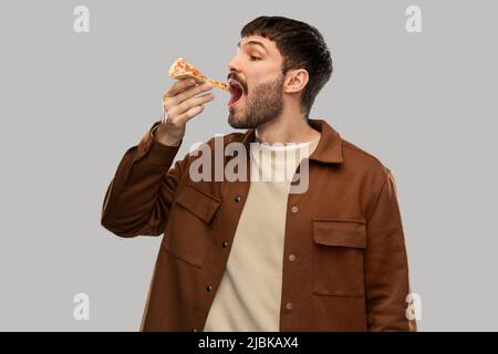 Hungriger junger Mann, der Pizza isst Stockfoto