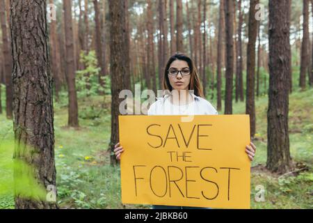 Junge Frau freiwillig in den Wäldern Streikposten und hält ein Plakat speichern den Wald Stockfoto