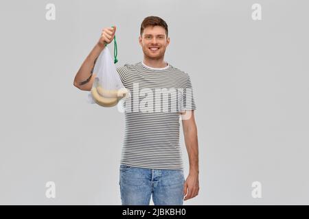 Glücklicher Mann mit wiederverwendbarem Saitenbeutel und Bananen Stockfoto