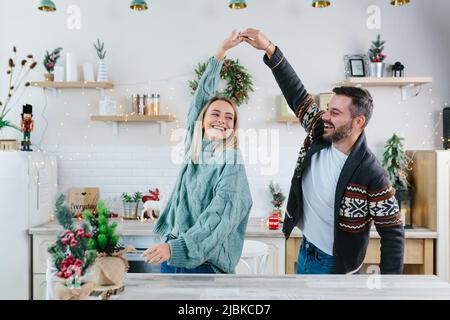 Junges Paar Ehemann und Frau glücklich Vorbereitung für Neujahr und Weihnachtsfeier, Familie Spaß beim Tanzen in der Küche Stockfoto