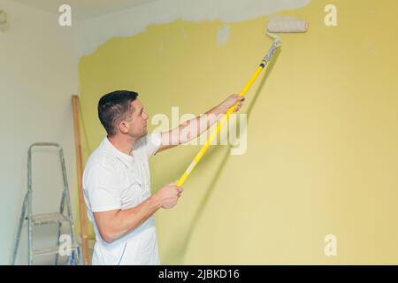 Arbeiter Mann trägt Farbe und Kitt auf die Wände in der Wohnung, macht Reparaturen in einem neuen Haus Stockfoto