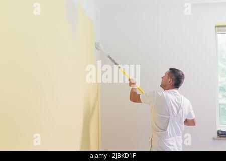 Arbeiter Mann trägt Farbe und Kitt auf die Wände in der Wohnung, macht Reparaturen in einem neuen Haus Stockfoto