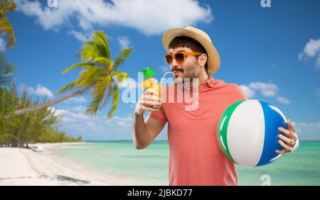 Glücklicher Mann in Strohhut mit Saft am Strand Stockfoto