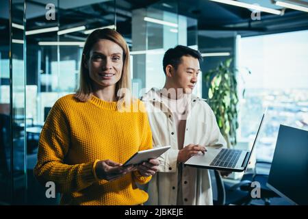 Porträt einer Programmiererin in einem modernen Büro, IT-Mitarbeiter arbeiten zusammen über ein neues Projekt, Asian Mann mit Laptop Stockfoto