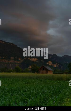 Dämmerung nach dem Sonnenuntergang in Dornbirn, Vorarlberg, Österreich. Tolle Stimmung mit interessanteren graublau Wolken, grünen Wiesen und Haus Stockfoto