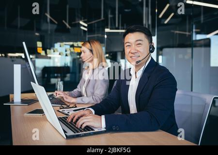 Männlicher asiatischer Geschäftsmann nutzt Headset für die Videokommunikation, Geschäftsmann blickt auf die Kamera und lächelt Stockfoto