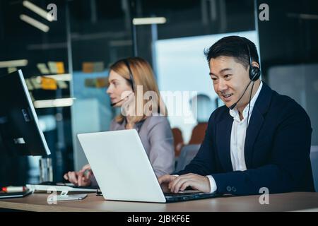 Ein Mitarbeiter des Happy Call Centers kommuniziert mit Kunden, berät bei Videoanrufen, aus der Ferne, ein asiatischer Geschäftsmann Stockfoto