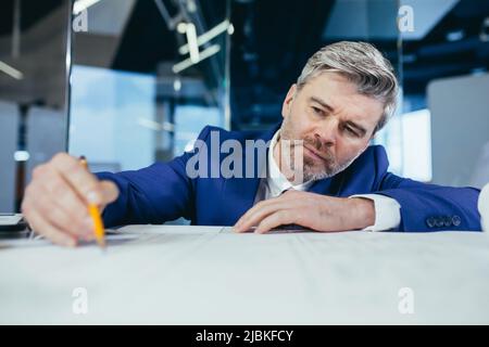 Nahaufnahme eines männlichen Architekten, grauhaariger Geschäftsmann zeichnet mit Bleistift einen Plan und eine Strategie der Unternehmensentwicklung auf Papier Stockfoto