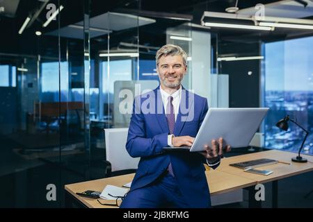 Porträt eines erfolgreichen grauhaarigen Geschäftsmannes, Mann mit der Arbeit in einem modernen Büro. Stockfoto