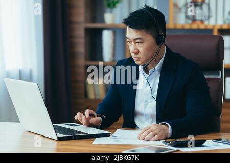 Asian Coach Business Coach unterrichtet Unternehmen, nutzt Kopfhörer für Videoanrufe und Laptop für Online-Schulungen Stockfoto