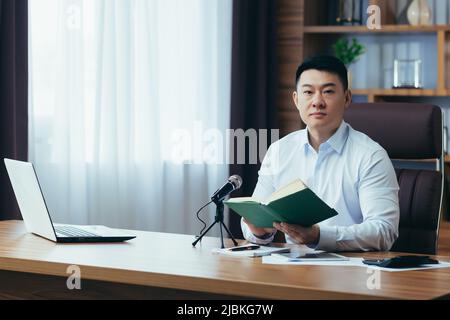 Asiatische Freiberufler nimmt Audio-Podcasts, Geschäftsmann arbeitet im Büro, verwendet professionelles Mikrofon und Laptop Stockfoto