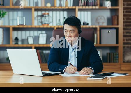 Asian Coach Business Coach unterrichtet Unternehmen, nutzt Kopfhörer für Videoanrufe und Laptop für Online-Schulungen Stockfoto