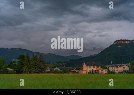 Dämmerung nach dem Sonnenuntergang in Dornbirn, Vorarlberg, Österreich. Tolle Stimmung mit interessanteren graublau Wolken, grünen Wiesen und Haus Stockfoto