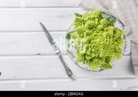 Romanesco Brokkoli Kopf auf einem weißen Holzhintergrund, Rohkohl aus biologischem Anbau bereit zum Kochen auf einem Schneidebrett Stockfoto