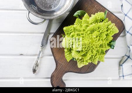 Romanesco Brokkoli Kopf auf einem weißen Holzhintergrund, Rohkohl aus biologischem Anbau bereit zum Kochen auf einem Schneidebrett Stockfoto