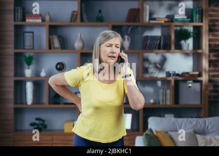 Die ältere Frau hat Rückenschmerzen, ruft einen Arzt zu Hause um Hilfe und Rat Stockfoto
