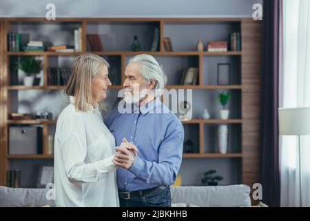 Glückliches Seniorenpaar Ehemann und Ehefrau haben Spaß beim Tanzen zu Hause und haben eine gute Zeit Stockfoto