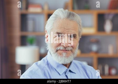 Nahaufnahme des Porträts eines alten Mannes zu Hause, der die Kamera ansah und lächelte Stockfoto
