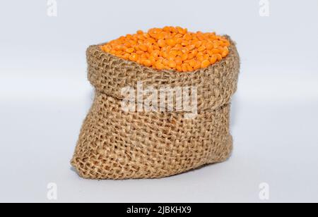 Orangefarbene Linsen im Jute-Beutel Stockfoto