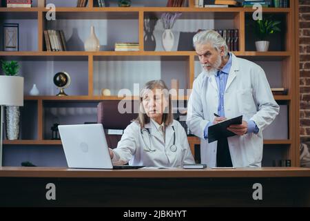 Oberärzte beraten und üben im klassischen Büro der Klinik, diskutieren die Diagnose der Patienten Stockfoto