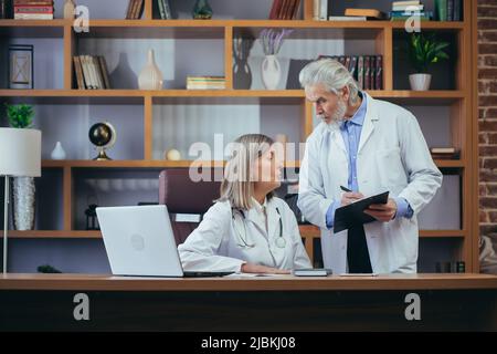 Oberärzte beraten und üben im klassischen Büro der Klinik, diskutieren die Diagnose der Patienten Stockfoto