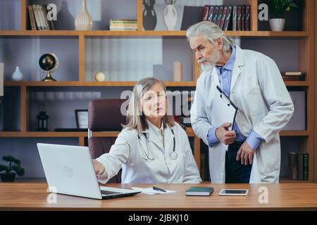 Oberärzte beraten und üben im klassischen Büro der Klinik, diskutieren die Diagnose der Patienten Stockfoto