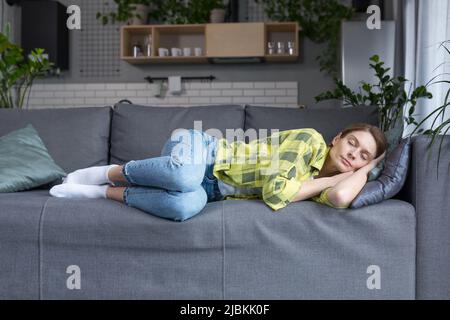 Eine Frau mittleren Alters zu Hause schläft allein auf einem Sofa, das sich von den Hausaufgaben ausruht Stockfoto