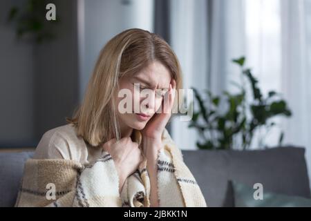Nahaufnahme, traurige und depressive Frau mittleren Alters, die allein auf der Couch zu Hause sitzt und weint Stockfoto