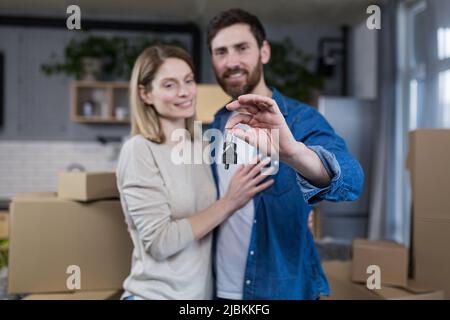 Ausgewählte Fokus, verheiratetes Paar Mann und Frau glücklich zusammen, umarmt, die Schlüssel zu ihrer neuen Wohnung, Hausarmung, Nahaufnahme Stockfoto