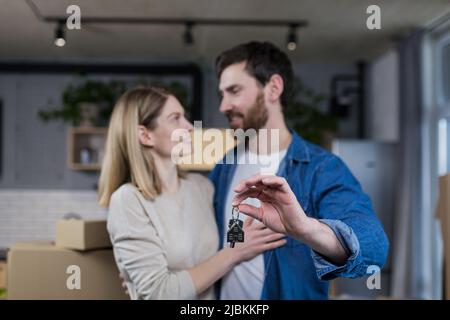 Ausgewählte Fokus, verheiratetes Paar Mann und Frau glücklich zusammen, umarmt, die Schlüssel zu ihrer neuen Wohnung, Hausarmung, Nahaufnahme Stockfoto
