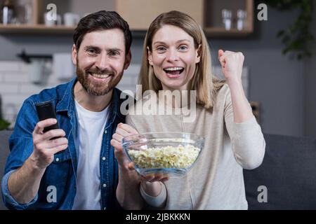 Foto des engen Paares Mann und Frau zusammen zu Hause Spaß haben und glücklich Fernsehen und Popcorn essen Stockfoto