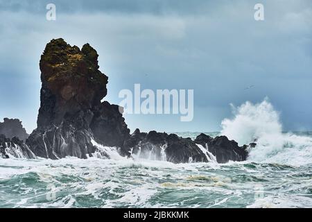 Ein großer Felsen in den brechenden Wellen des atlantischen Ozeans an der isländischen Westküste Stockfoto