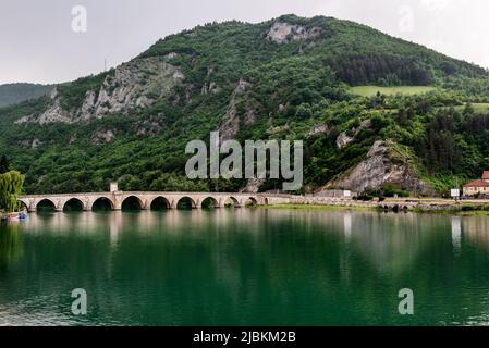 Die osmanische Mehmed Pasa Sokolovic Brücke in Visegrad, bosnische Berge, spiegelt sich im Fluss Drina, Bosnien und Herzegowina. Stockfoto