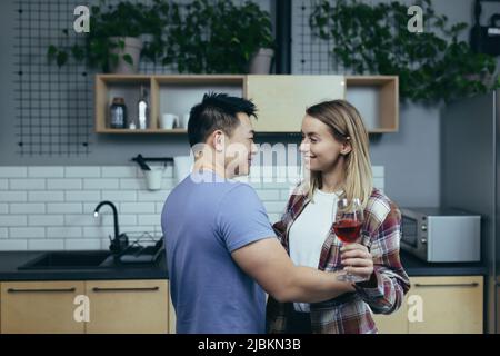 Junges Paar in der Liebe zu Hause feiert Jubiläum, Mann und Frau umarmen und tanzen, glückliche junge Familie Stockfoto