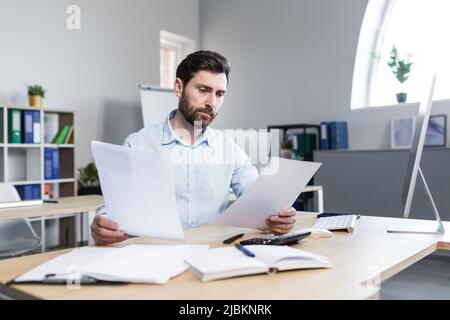 Denkender Geschäftsmann, der im Büro mit Dokumenten arbeitet, Mann, der Finanzberichte überprüft Stockfoto