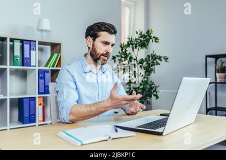 Erfolgreiche Geschäftsfrau schaut auf den Laptop-Bildschirm und spricht mit dem Mann bei der Arbeit im Büro Stockfoto