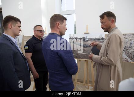 BUCHA, UKRAINE - 6. JUNI 2022 - Leiter der Kirche des heiligen Andreas der erste genannte Apostel Andrii Halavin zeigt die Fotografien von Massenbestattungen Stockfoto