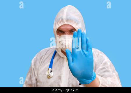 Mann Arzt Sanitäter in einem Schutzanzug Uniform mit Brille und Gesichtsmaske auf einem Studio blauen Hintergrund. Sanitäter in weißer antiviraler Schutzkleidung Stockfoto