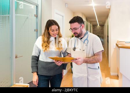 Männlicher Arzt im Gespräch mit weiblichen Patienten, die im medizinischen Zentrum behandelt werden. Stockfoto