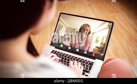 Lächelnde kaukasische Geschäftsfrau, die während einer Videokonferenz mit einer asiatischen Kollegin gestikuliert Stockfoto