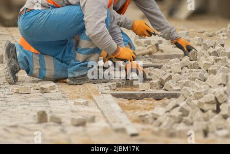 Pflastersteine legen und einen neuen Bürgersteig in der Stadt schaffen. Prag, Tschechische Republik. Menschen mit Körperteilen. Stockfoto