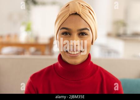 Nahaufnahme eines lächelnden jungen Birazialen, das zu Hause Kopftuch trägt Stockfoto