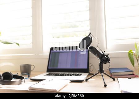 Kondensatormikrofon mit Laptop auf dem Tisch am Fenster im Heimstudio Stockfoto