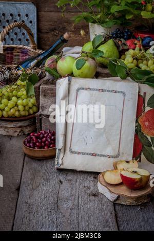 Stillleben im Herbst. Früchte und Beeren. Äpfel, Trauben, Erdbeeren, Pflaumen auf einem Holztisch. Landhausstil. Leere gesunde Vitaminnahrung. Obsternte. Stockfoto