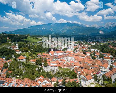 Luftbild mittelalterliche Stadt kamnik umgeben von üppigen Bäumen in den Kamnik-Savinja Alpen mit traditionellen slowenischen Häusern mit roten Dachziegeln. Stockfoto