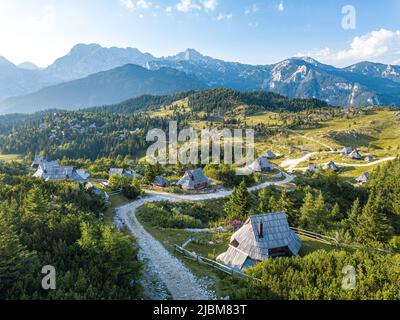 Wunderschöne Drohnenaufnahme von Holzhütten in Velika Planina, mit Ferienhäusern entlang Schotterstraßen in den slowenischen alpen Stockfoto